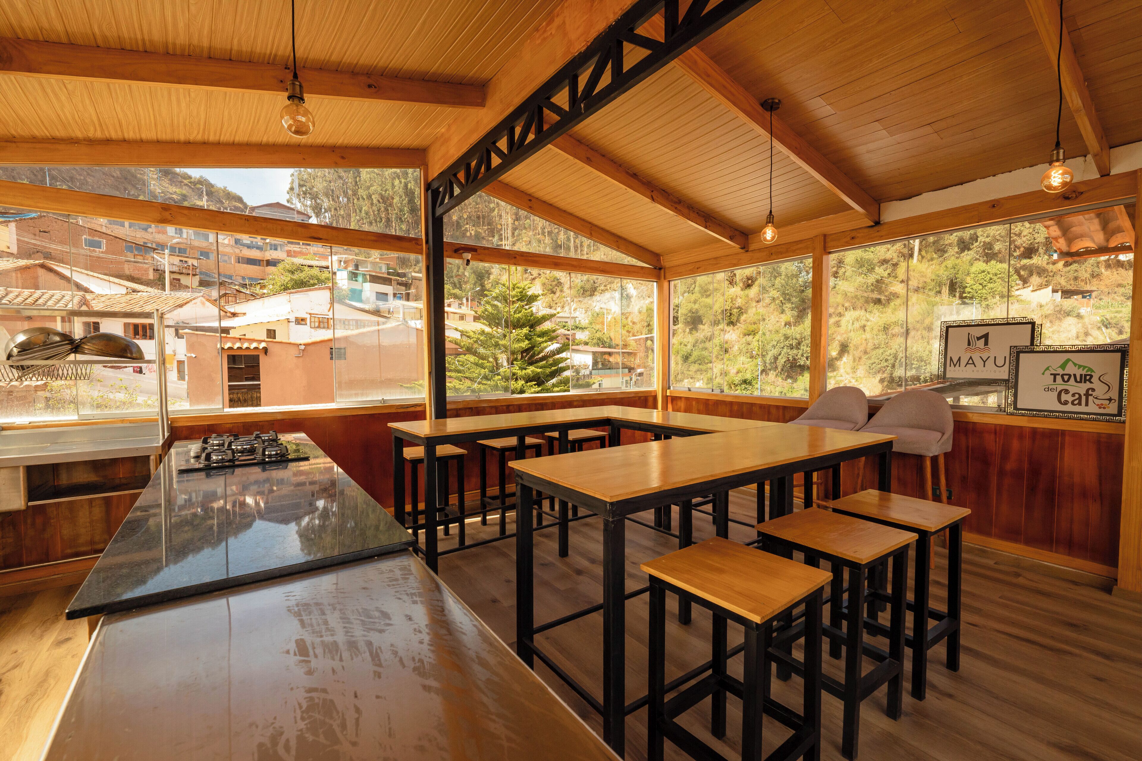 A modern kitchen with a central island, wooden tables, and bar stools.