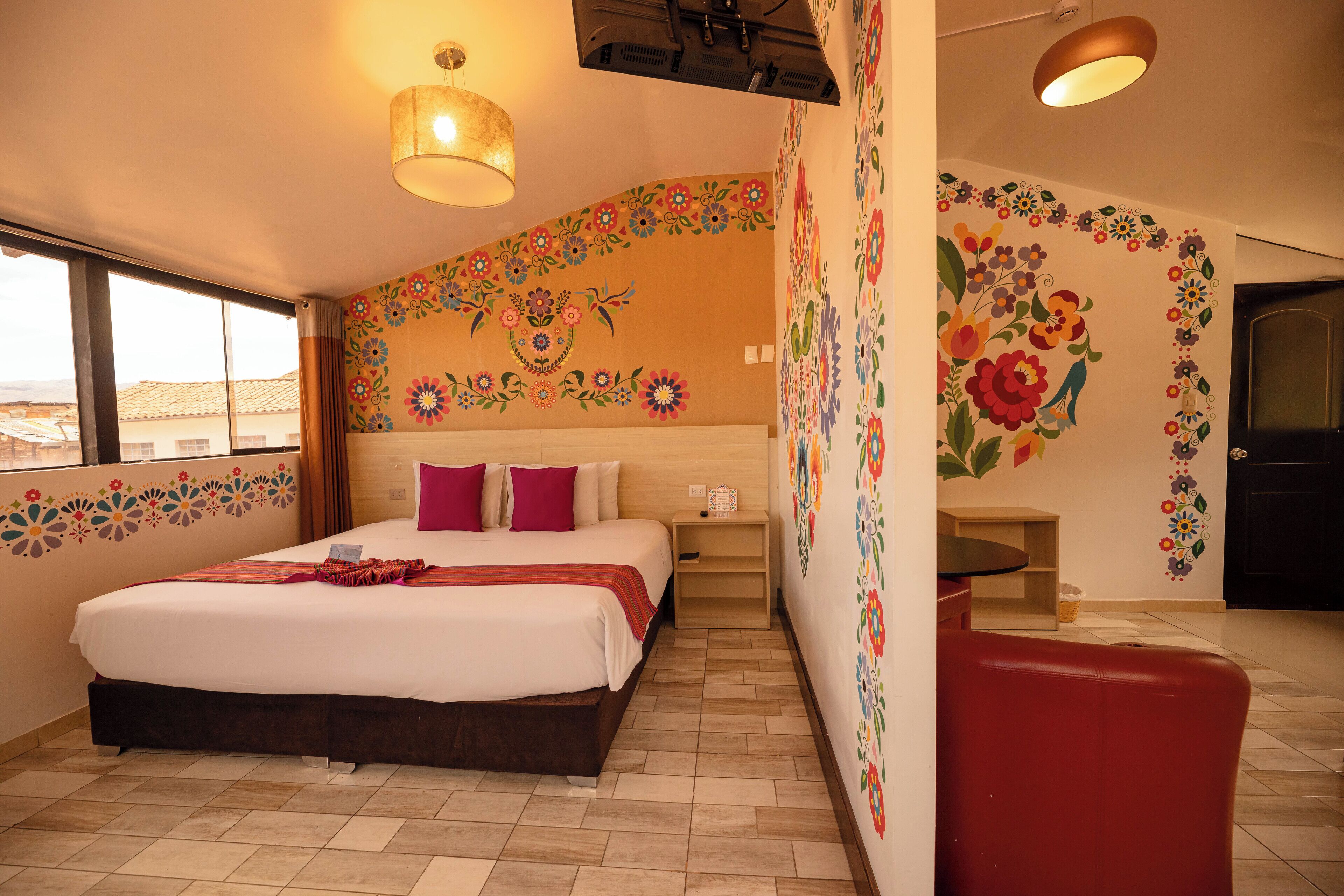 Un dormitorio con una cama grande, una silla roja y adornos florales en la pared.