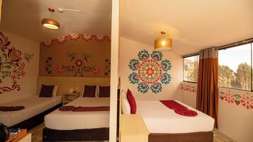 A room with two beds, a wooden desk, and a large window with curtains.