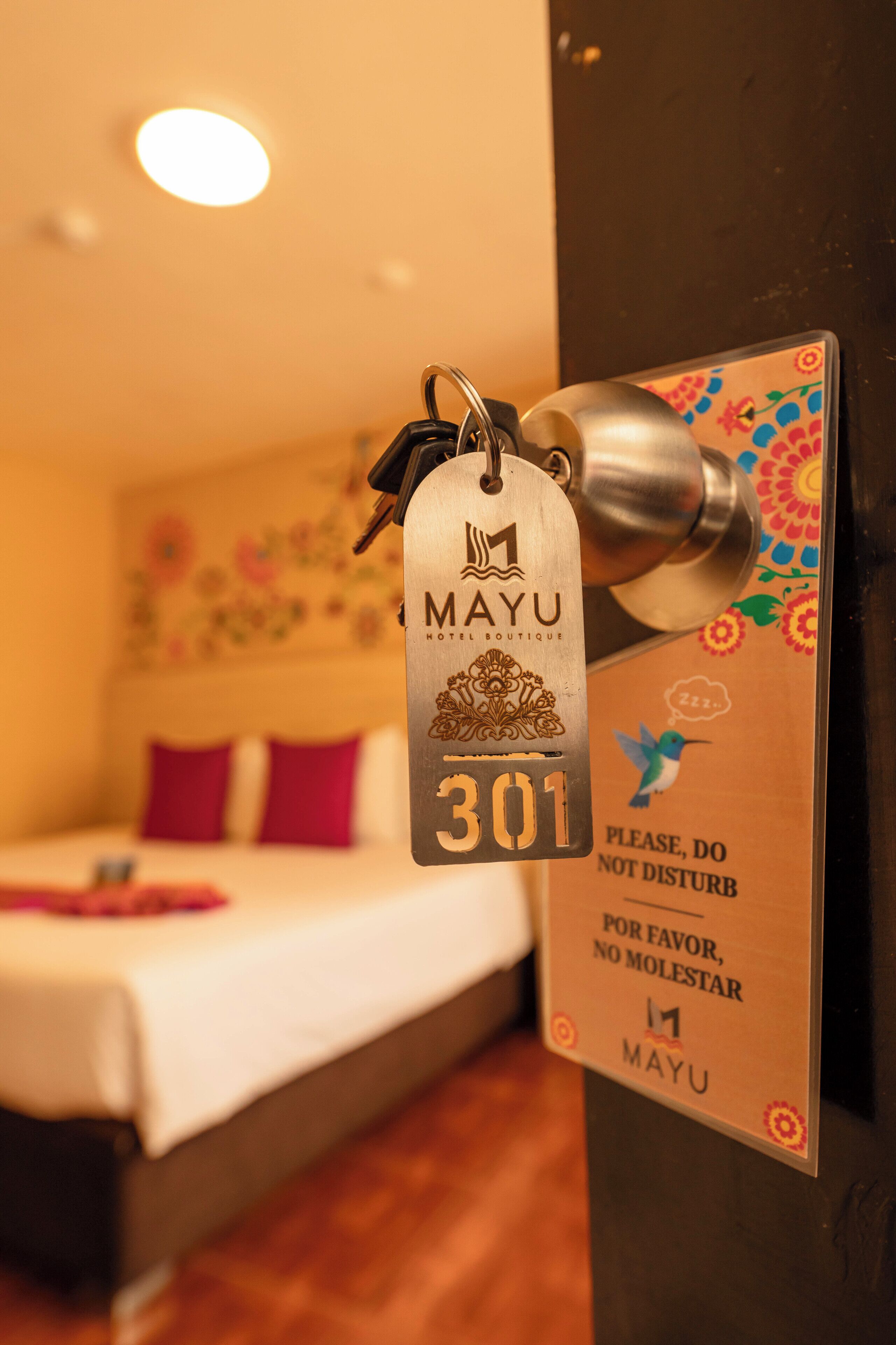 A hotel room with a bed, a door with a keycard, and a sign requesting guests not to disturb.