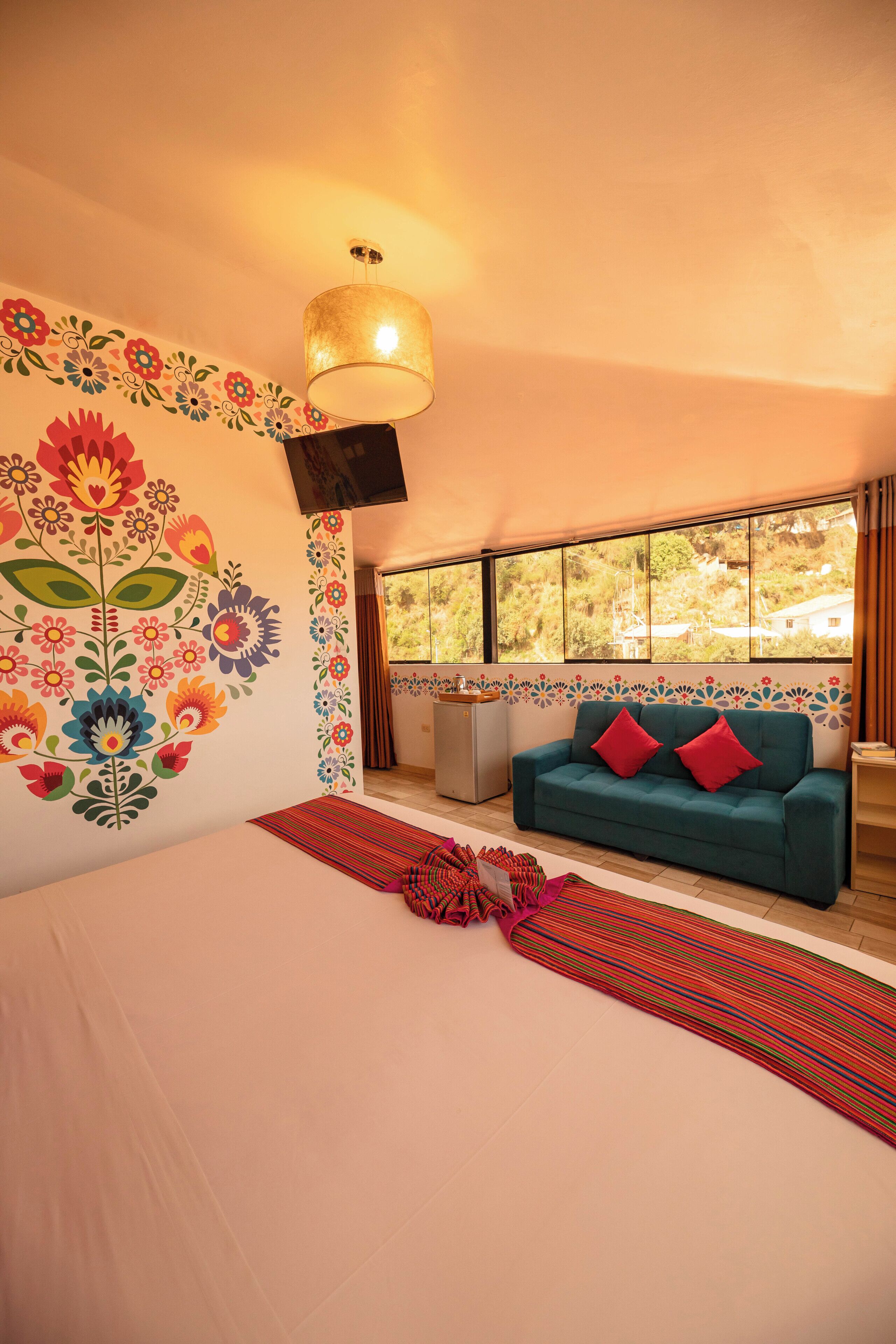 Une pièce comprenant un lit, un canapé, une fenêtre donnant sur un beau paysage et un mur décoré de motifs floraux.