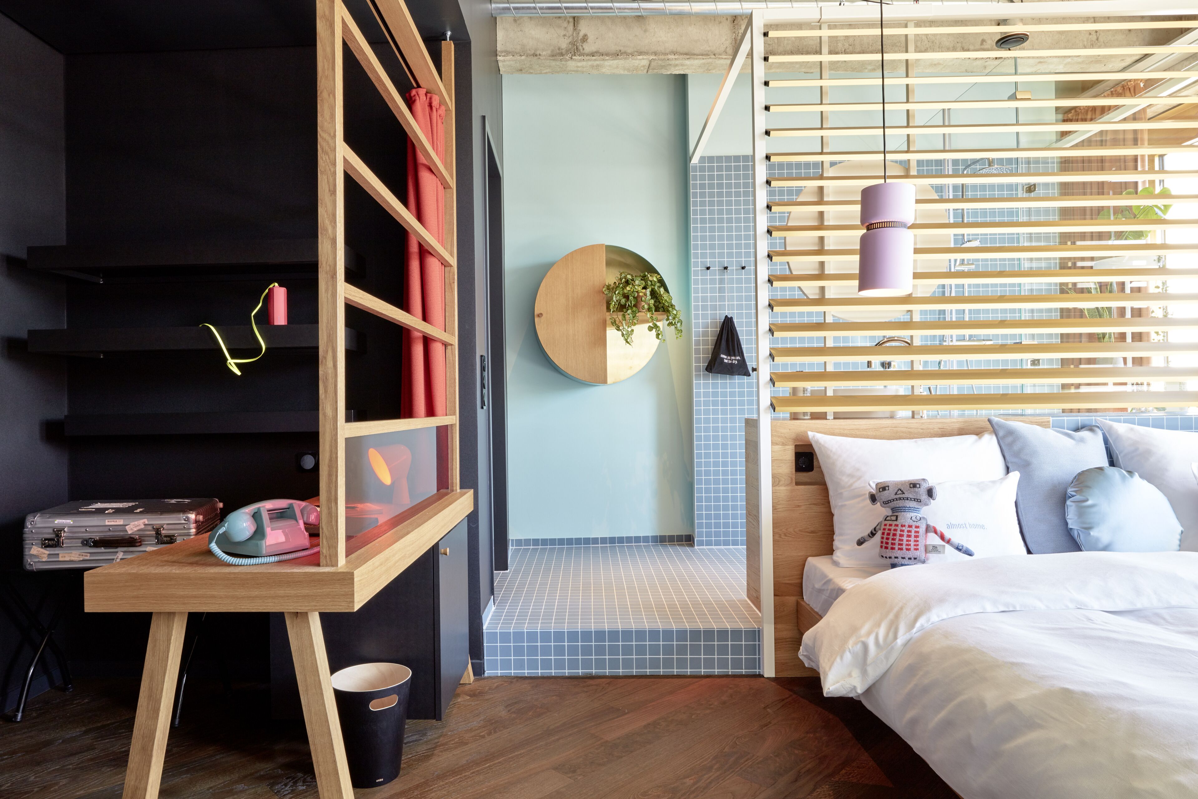 A modern bedroom with a bed, a desk, and a circular wall-mounted shelf.