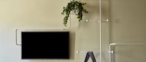 A wall-mounted TV, a shelf with a book and a cup, and a hanging bag with a space-themed design.