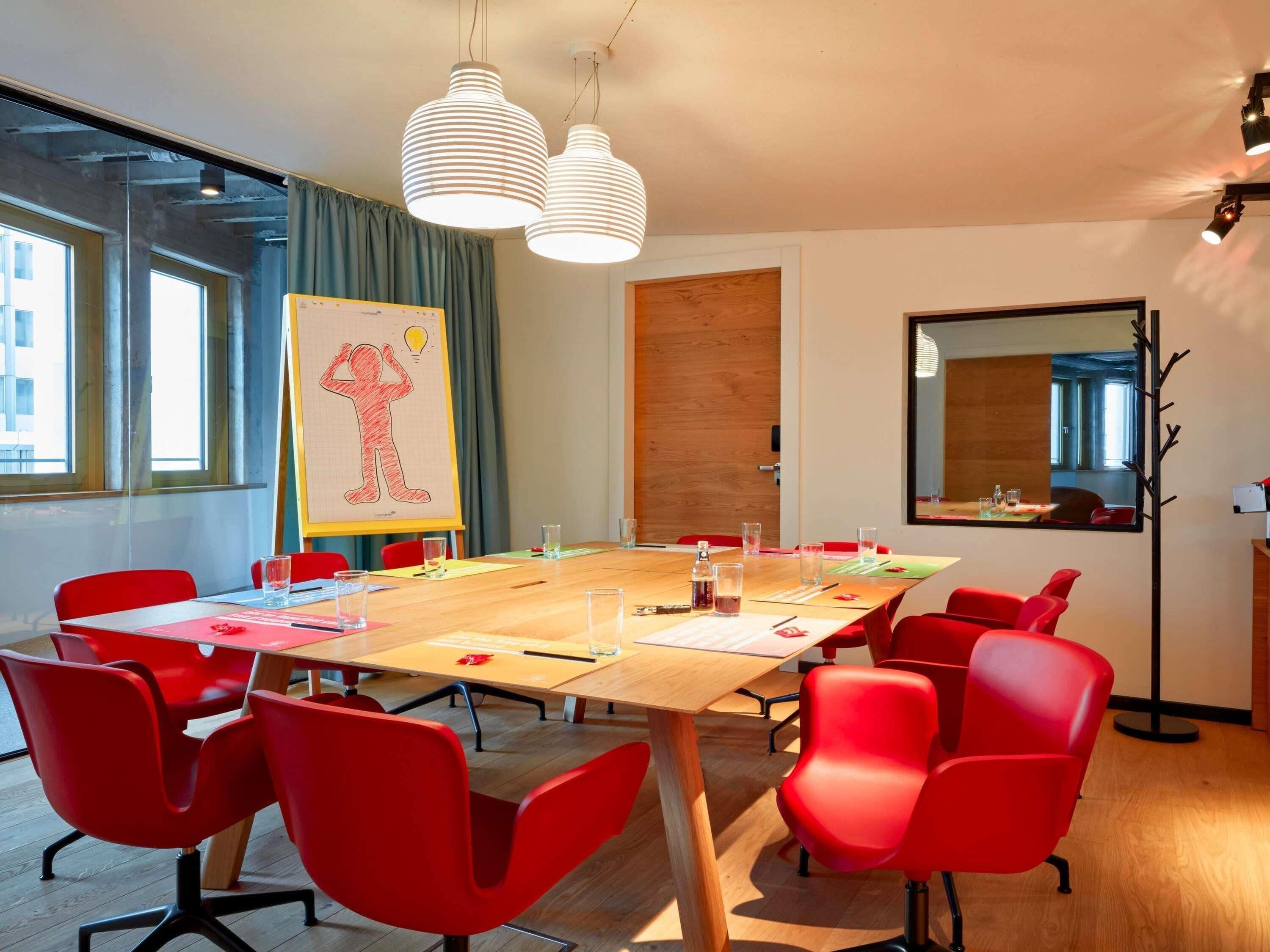 A conference room with a large table, red chairs, and a whiteboard with a drawing.