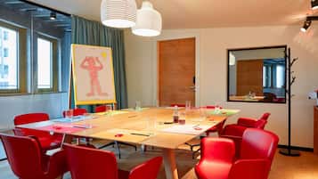 A conference room with a large table, red chairs, and a whiteboard with a drawing.