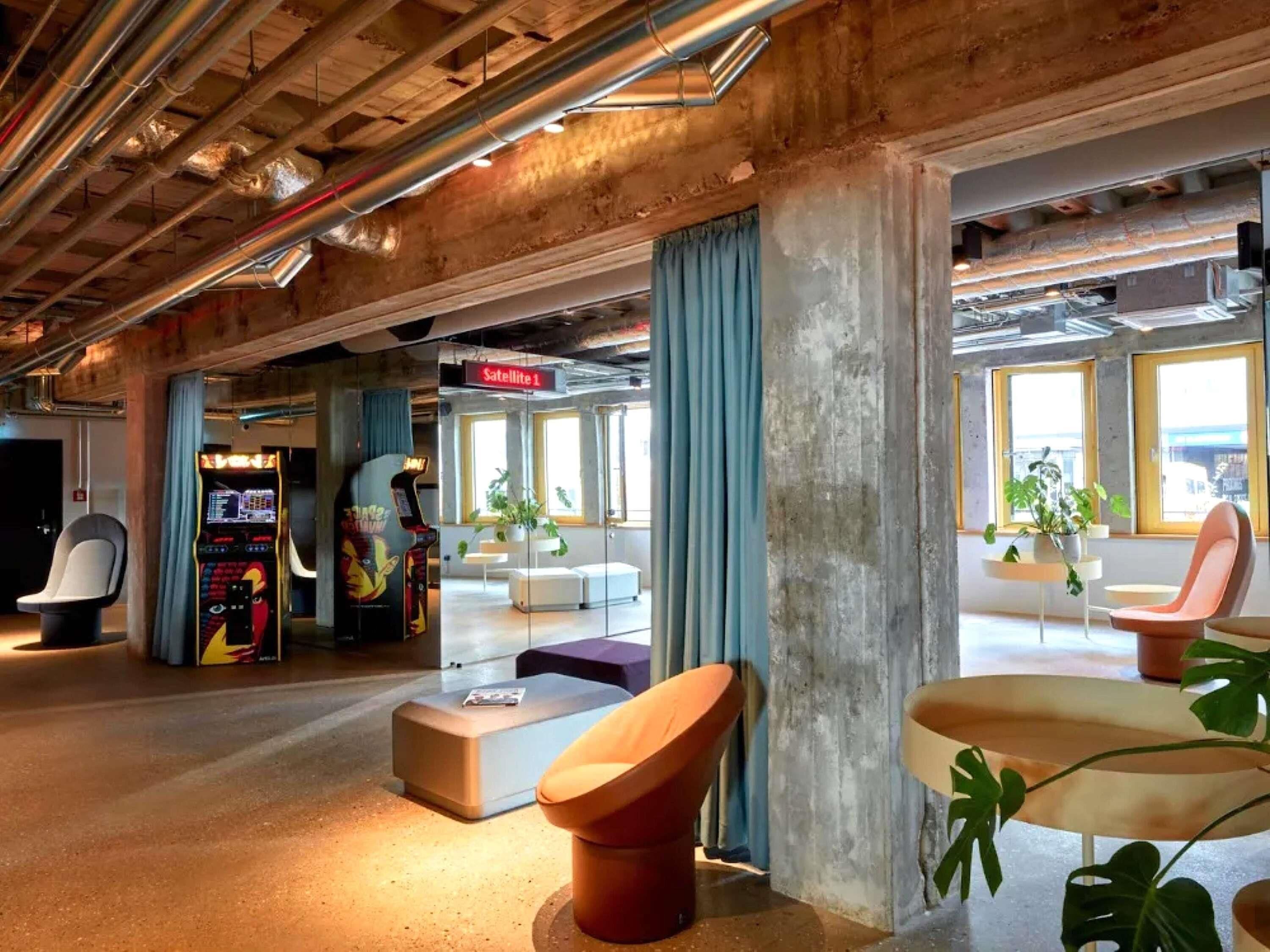 Un área de descanso moderna con juegos de arcade, asientos cómodos y ventanas amplias.
