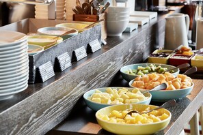 A buffet with various food items including fruits and vegetables. - 25hours Hotel The Circle (Cologne)