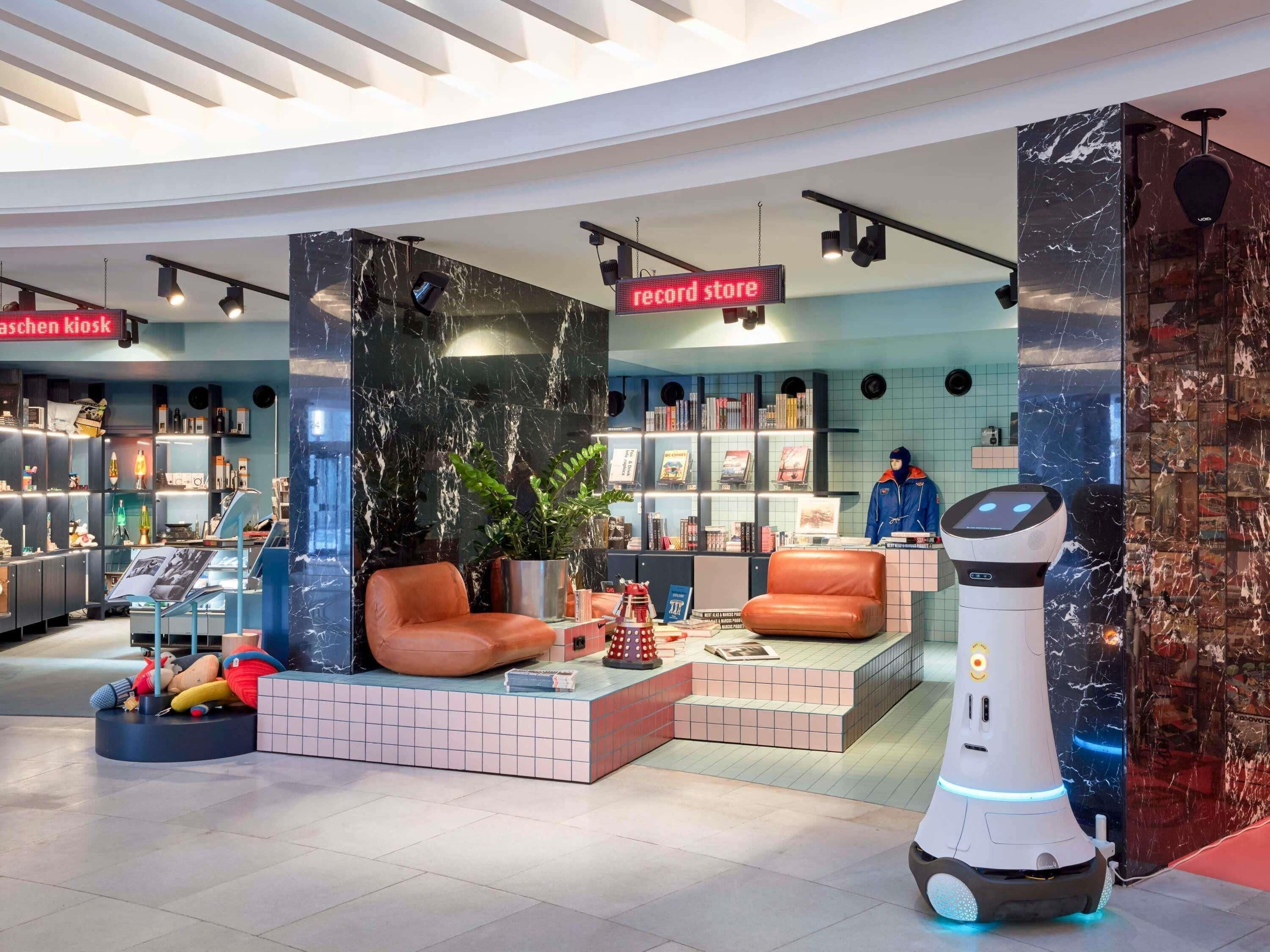 A modern record store with a seating area, bookshelves, and a robot.