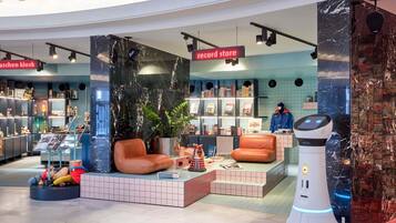 A modern record store with a seating area, bookshelves, and a robot.
