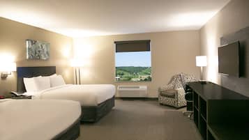 Una camera d'albergo con due letti, una scrivania, una sedia, una televisione, una finestra con vista e un quadro appeso al muro.