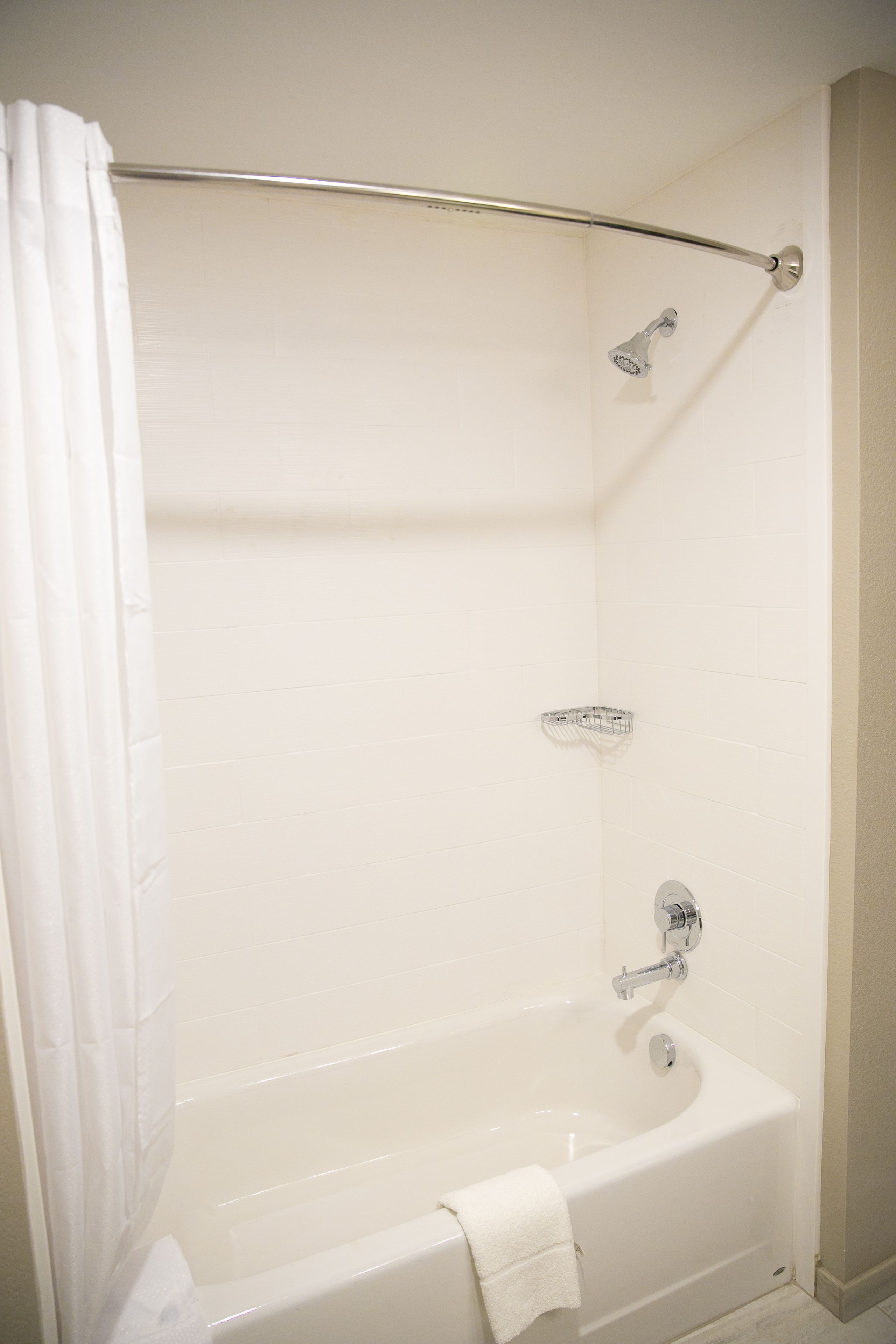 A white bathtub with a showerhead and a towel hanging on the side.