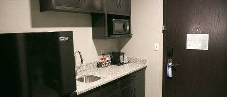 A compact kitchen with a refrigerator, microwave, and sink.
