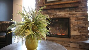 Un salon avec une cheminée en pierre, un canapé en cuir et une grande plante verte dans un vase.