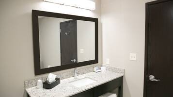 A bathroom with a large mirror, a sink, and a dark door.