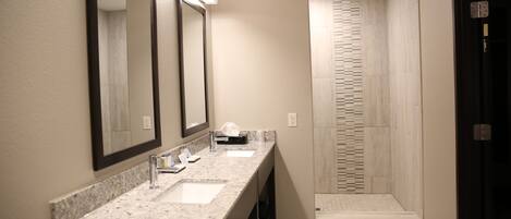 A modern bathroom with a granite countertop, two sinks, and a large mirror.