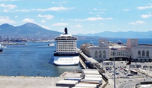 Navio de cruzeiro atracado em um porto, com montanhas ao fundo.