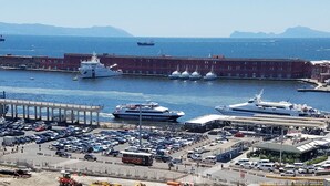 A harbor with boats, a parking lot, and buildings. - Maschio Angioino Suite (Naples)