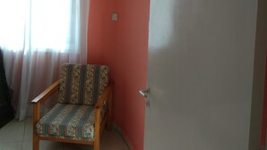 Una habitación con una sola silla, una puerta blanca y un equipo de aire acondicionado montado en la pared.