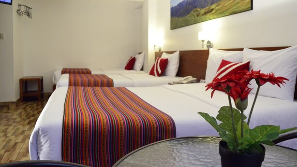 A hotel room with two beds, a small table, a potted plant, and a painting on the wall. - Viandina Machupicchu (Machu Picchu)