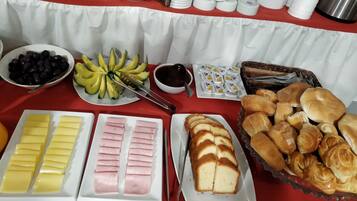 Una mesa de bufé con diversos alimentos, entre ellos frutas, quesos, carnes y pasteles.