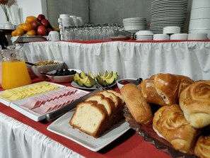 Una mesa de buffet con diferentes alimentos, como pan, queso, jamón y frutas.