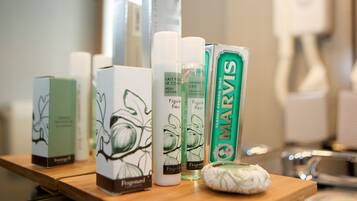 Diversos produtos de higiene pessoal sobre uma superfície de madeira, incluindo loção corporal, shampoo e sabonete em barra.
