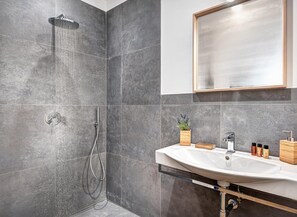 A modern bathroom with a shower, a sink, and a mirror. - Sorrento Lux Suites - Blue (Sorrento)