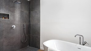 A modern bathroom with a shower, a bathtub, and a small shelf with toiletries. - Sorrento Lux Suites - Blue (Sorrento)