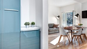A modern kitchen with a blue cabinet and a dining area with a wooden table and chairs. - Sorrento Lux Suites - Blue (Sorrento)