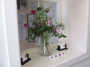 A vase with flowers on a counter near a window. - Alexandra Guest House (Hemel Hempstead)