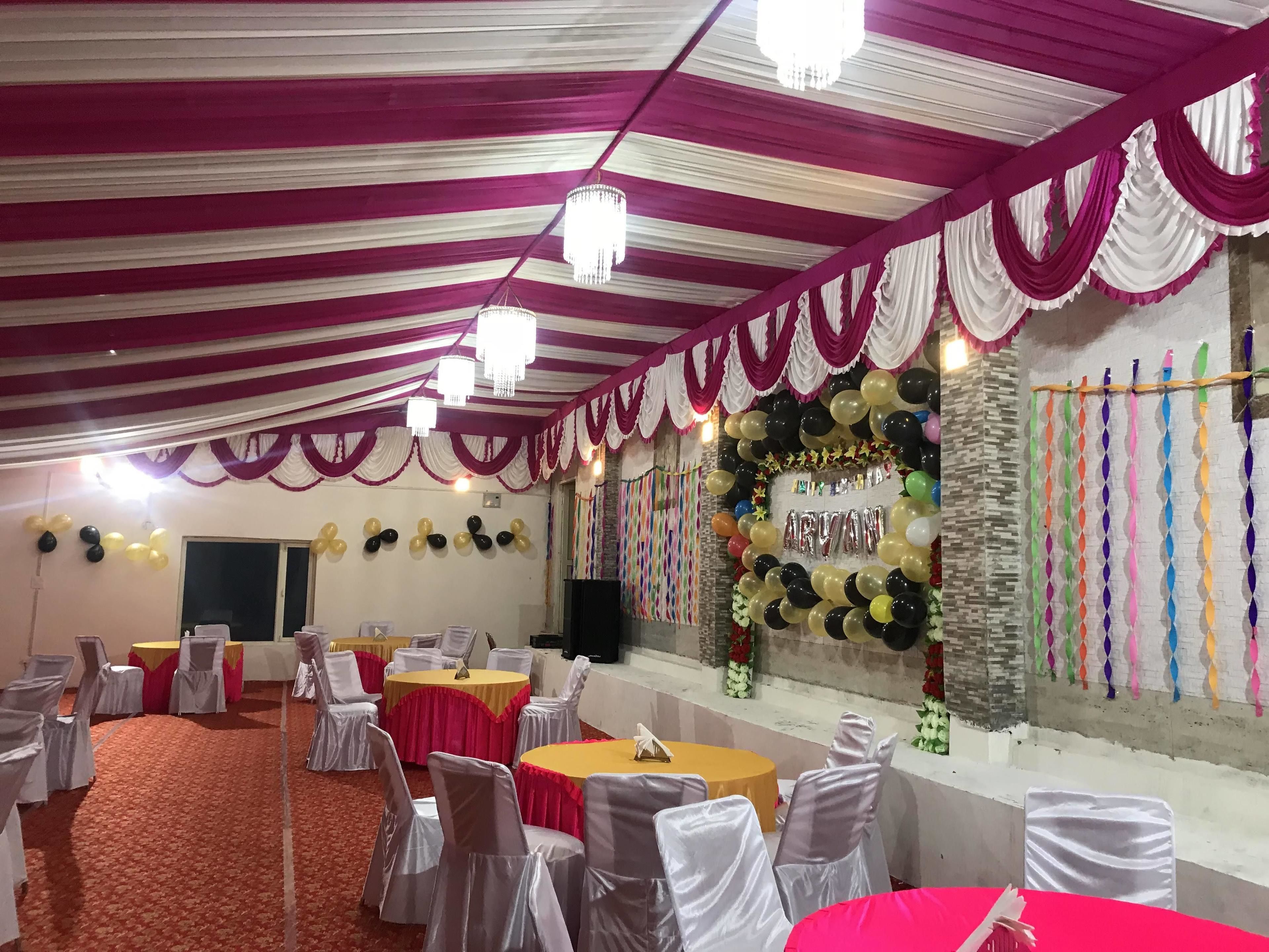 A banquet hall with round tables, white and red tablecloths, and chairs with white covers.