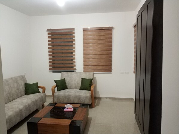 A living room with a sofa, armchairs, a coffee table, and two windows with blinds. - Cana Palace (Kfar Cana)