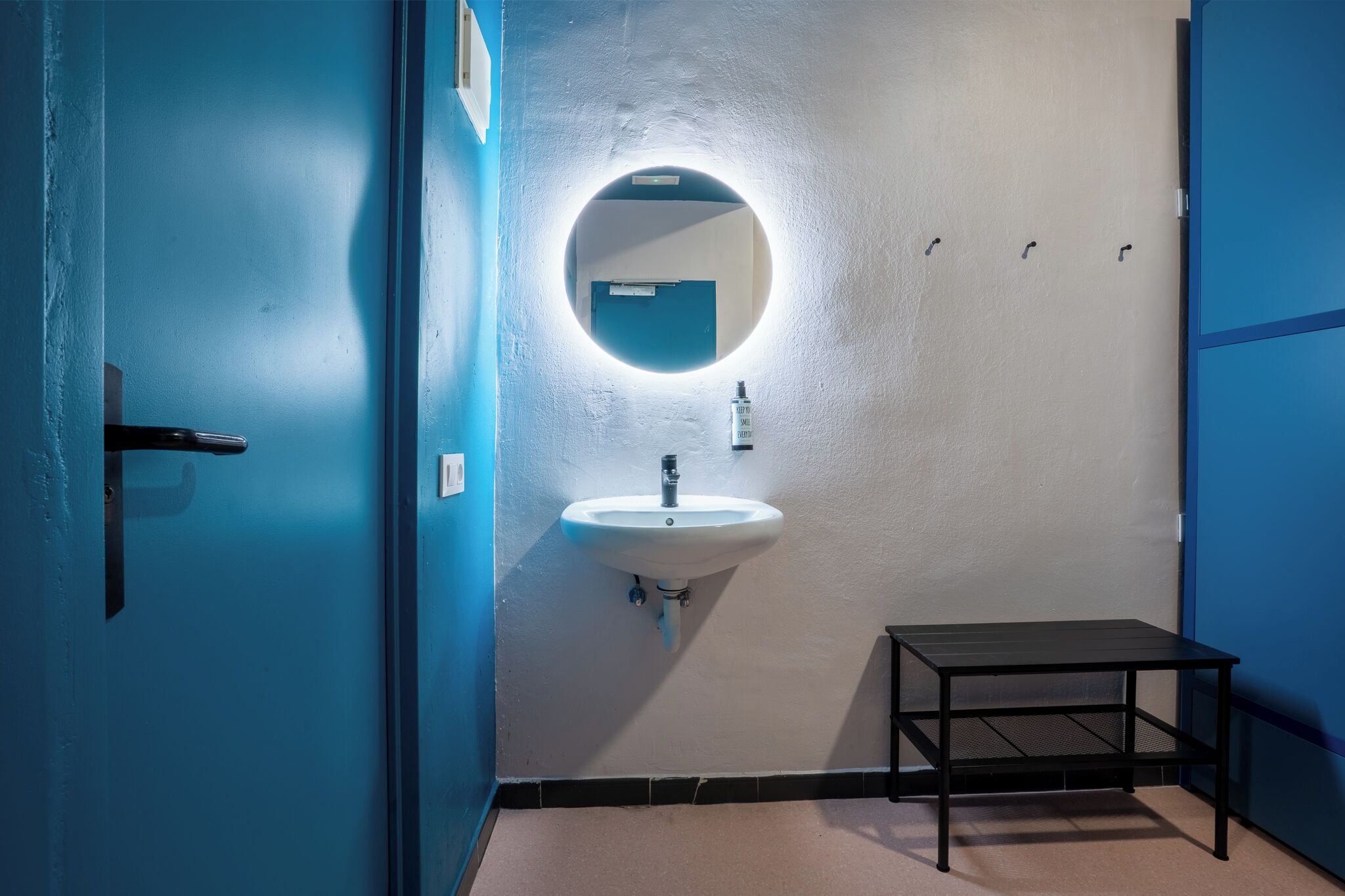 A bathroom with a sink, mirror, and a small table.