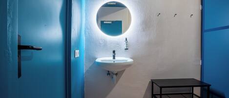 A bathroom with a sink, mirror, and a small table.