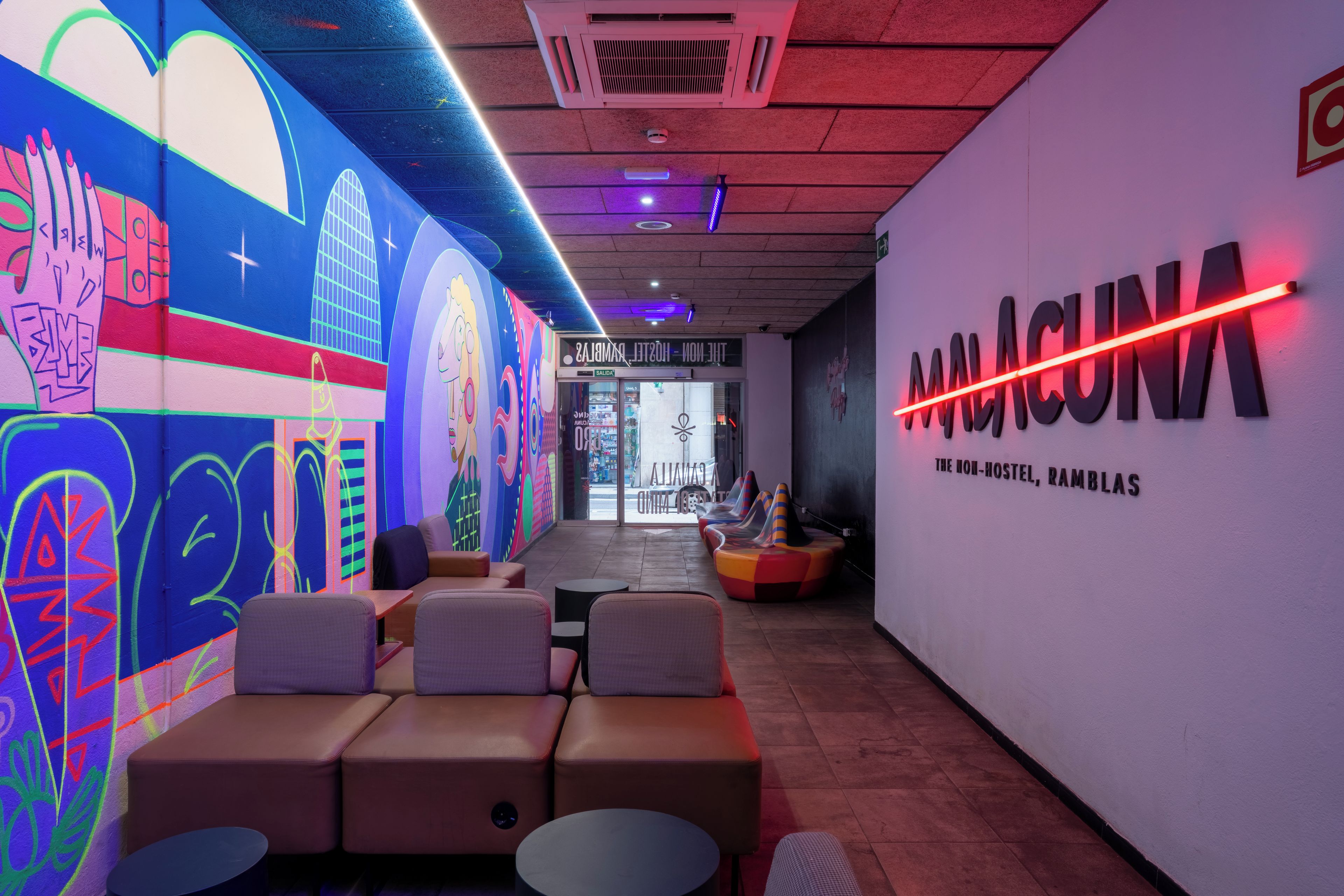 Ein modernes Interieur mit einem farbenfrohen Wandgemälde, einer Neonreklame und einer Sitzecke.