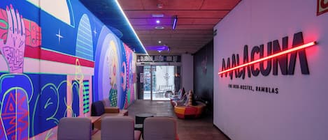 Ein modernes Interieur mit einem farbenfrohen Wandgemälde, einer Neonreklame und einer Sitzecke.