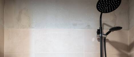 A bathroom with a shower, toilet, and a bottle of hand soap on the wall.