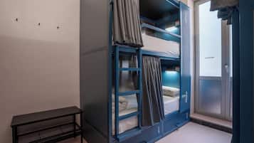 A dormitory room with bunk beds, a small table, and a door with a frosted glass panel.