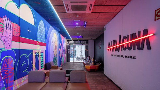 Un interior moderno con un letrero de neón, murales coloridos y zonas de estar.