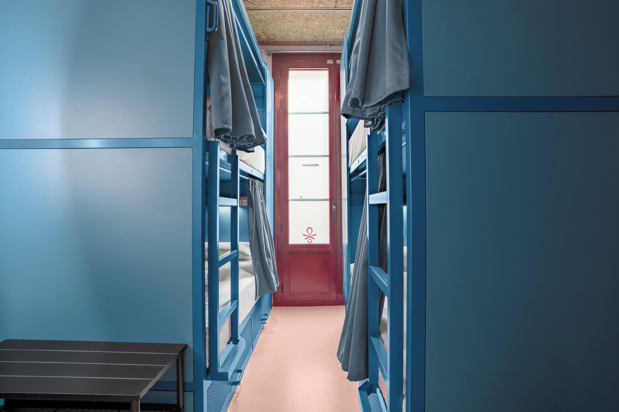 A narrow hallway with bunk beds on either side and a table at the end.