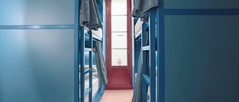 A narrow hallway with bunk beds on either side and a table at the end.