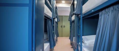 A narrow corridor with bunk beds on both sides, a carpeted floor, and a door at the end.