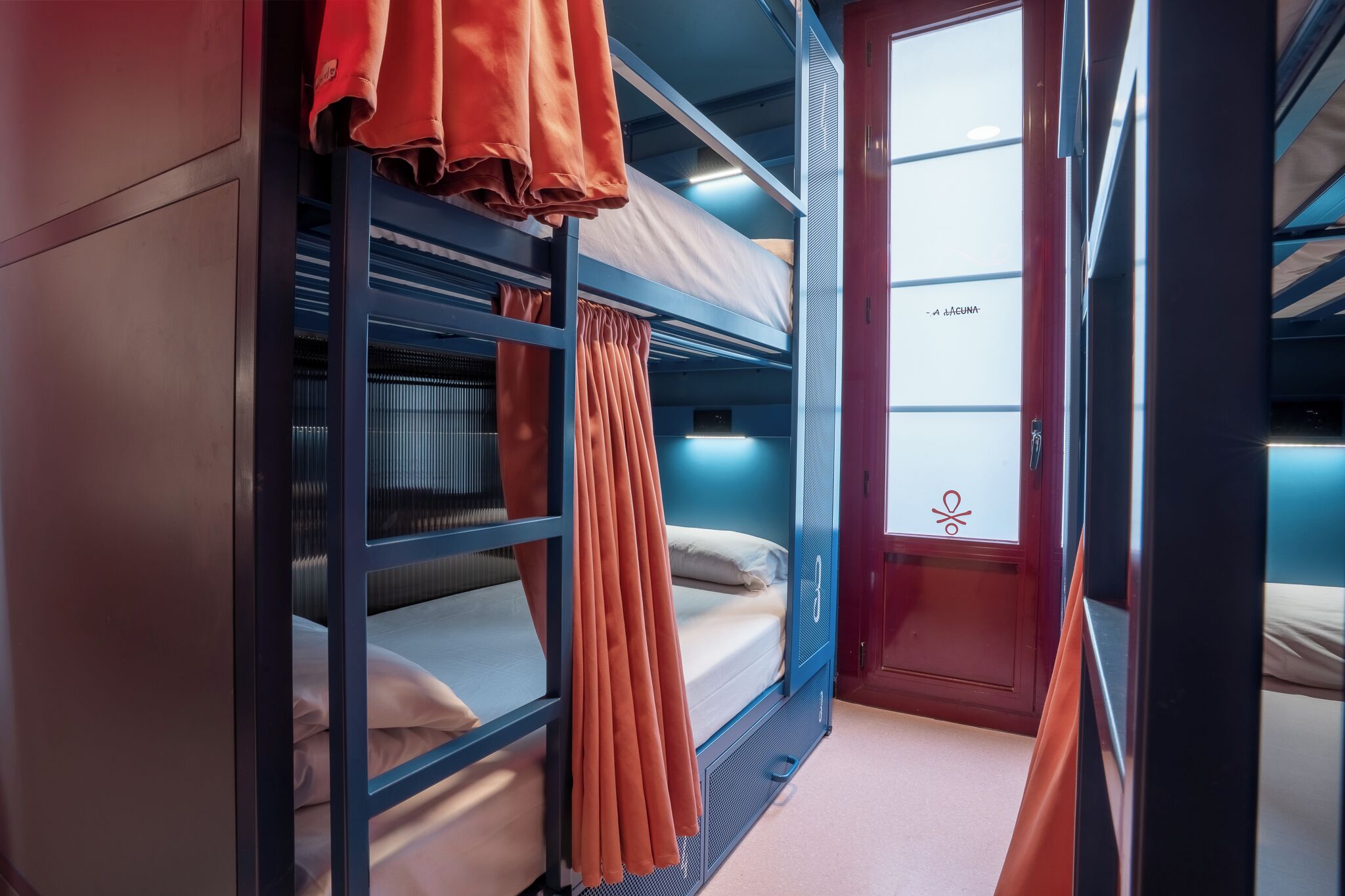 A train compartment with bunk beds, curtains, and a window with a view.