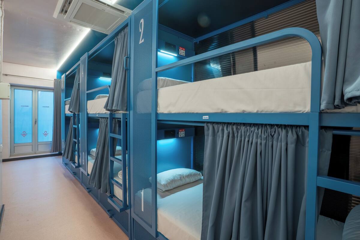 Een treinwagon met slaapplaatsen, gordijnen en een raam met zonwering.