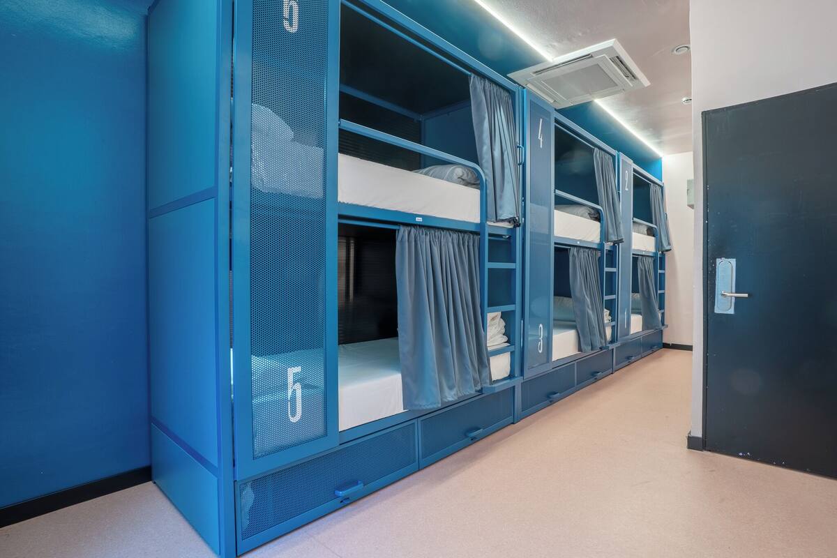 Een slaapzaal met stapelbedden, kamer nummer 5, en een zwarte deur.