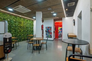 Un espacio interior moderno con mesas y sillas, una pared verde y una puerta roja.