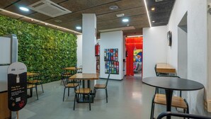 Un espacio interior moderno con pared verde, mesas y sillas de madera.
