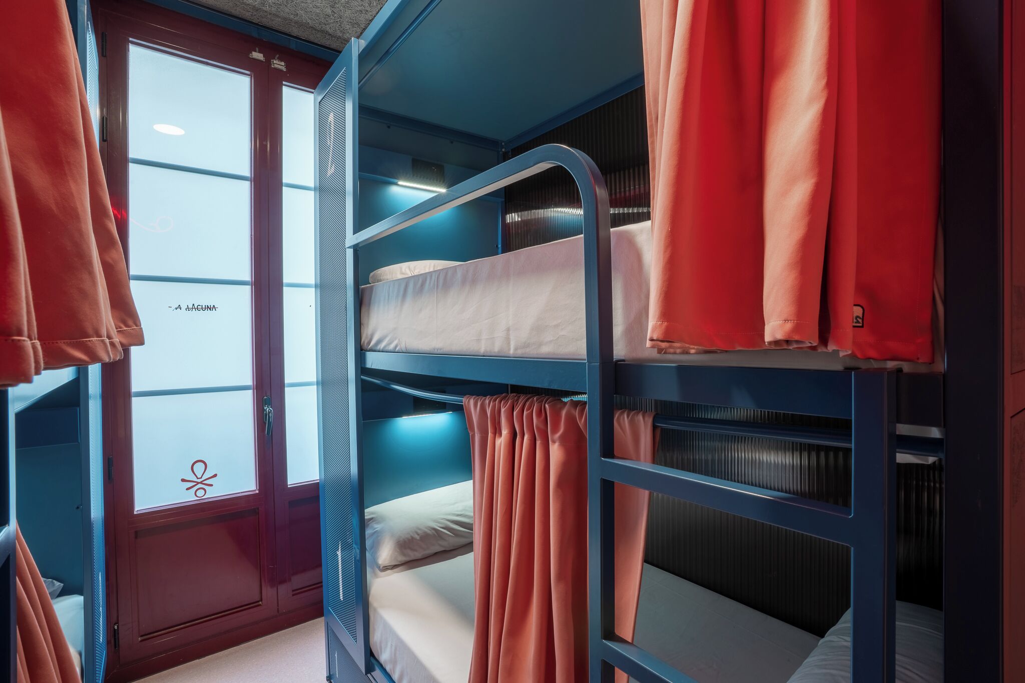 A bunk bed room with curtains, a window, and a door.