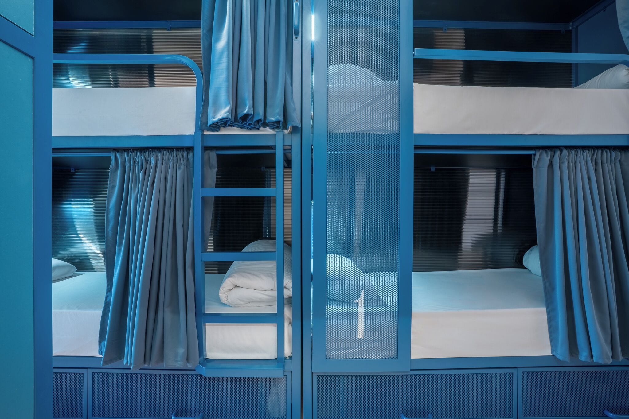 A bunk bed room with curtains and a mesh screen.