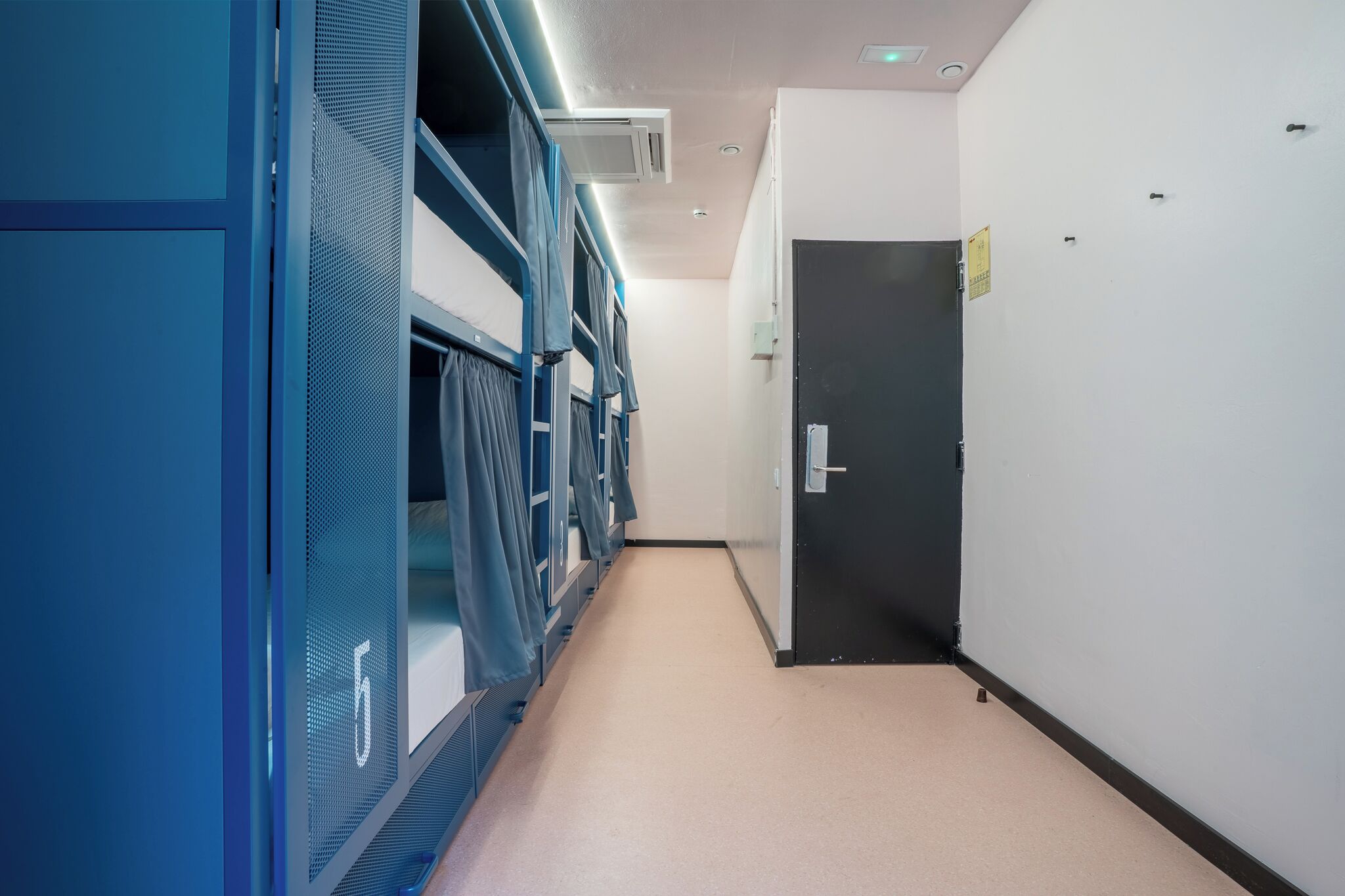 A hallway with bunk beds, a door, and a sign on the wall.
